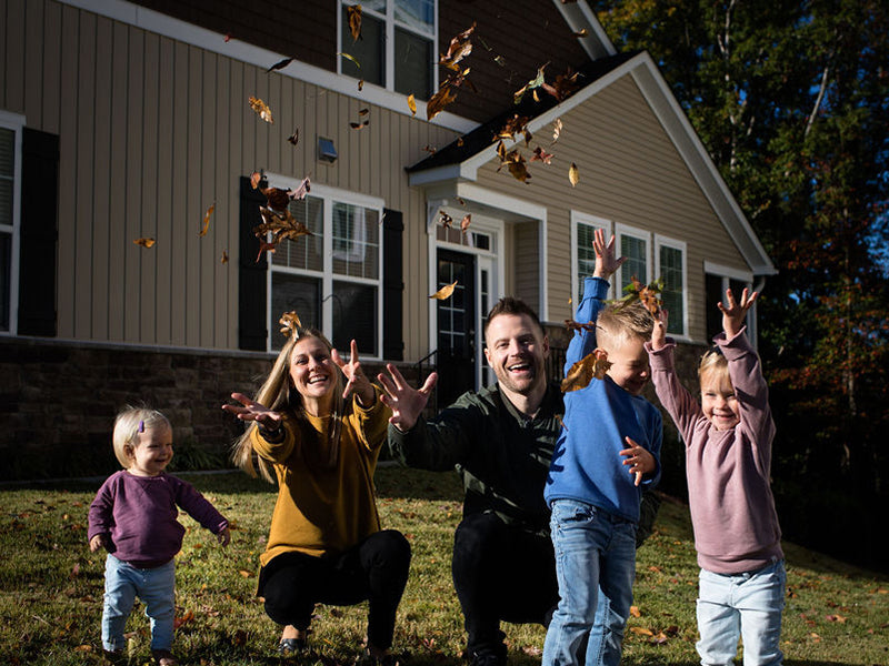 happy family tossing leaves in the front yard